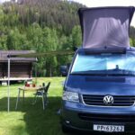 Blue VW Californian campervan with roof tent and outside sitting area.